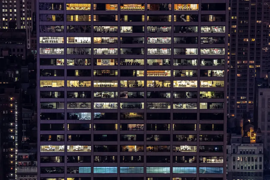 Office tower lit up at night, teams still at work